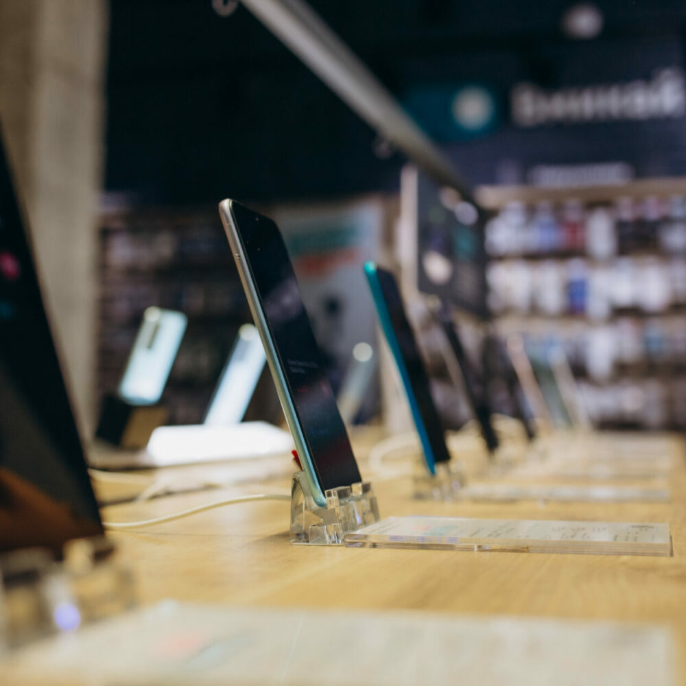Showcase with smartphones in the modern electronics store. Buy a mobile phone. Many smartphones on the shelf of the technology store